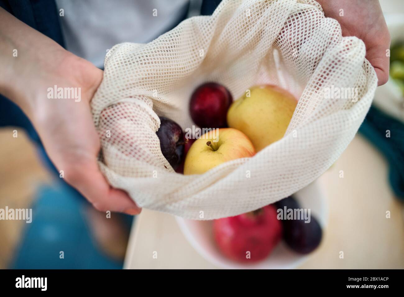 Mittelteil der Frau, die Früchte in wiederverwendbaren Beutel im Innenbereich hält, nachhaltiger Lebensstil. Stockfoto