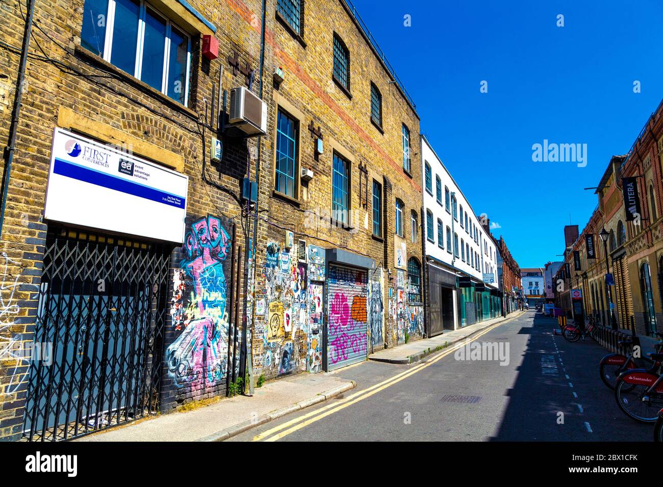 Ziegelwand mit Graffiti, Tags und Plakaten in Fashion Street, Spitalfields, London, Großbritannien Stockfoto