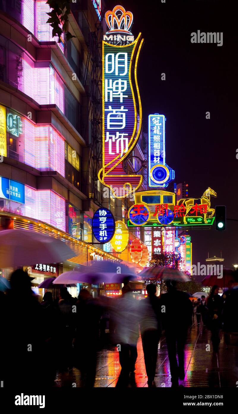 Shanghai, China, Asien - Neon-Zeichen an der Nanjing Road, der wichtigsten Handelsstraße der Stadt und Menschen unter dem Regen. Stockfoto