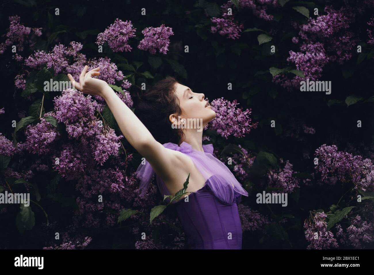 Schöne junge Frau im Garten mit blühenden Flieder. Stockfoto