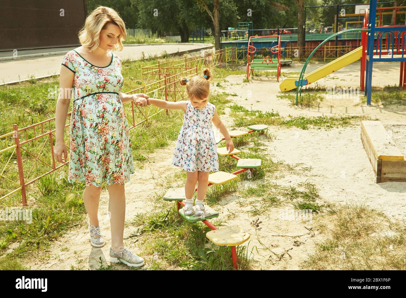 Aktives kleines Mädchen auf dem Spielplatz. Spielendes Kind mit Mutter. Stockfoto