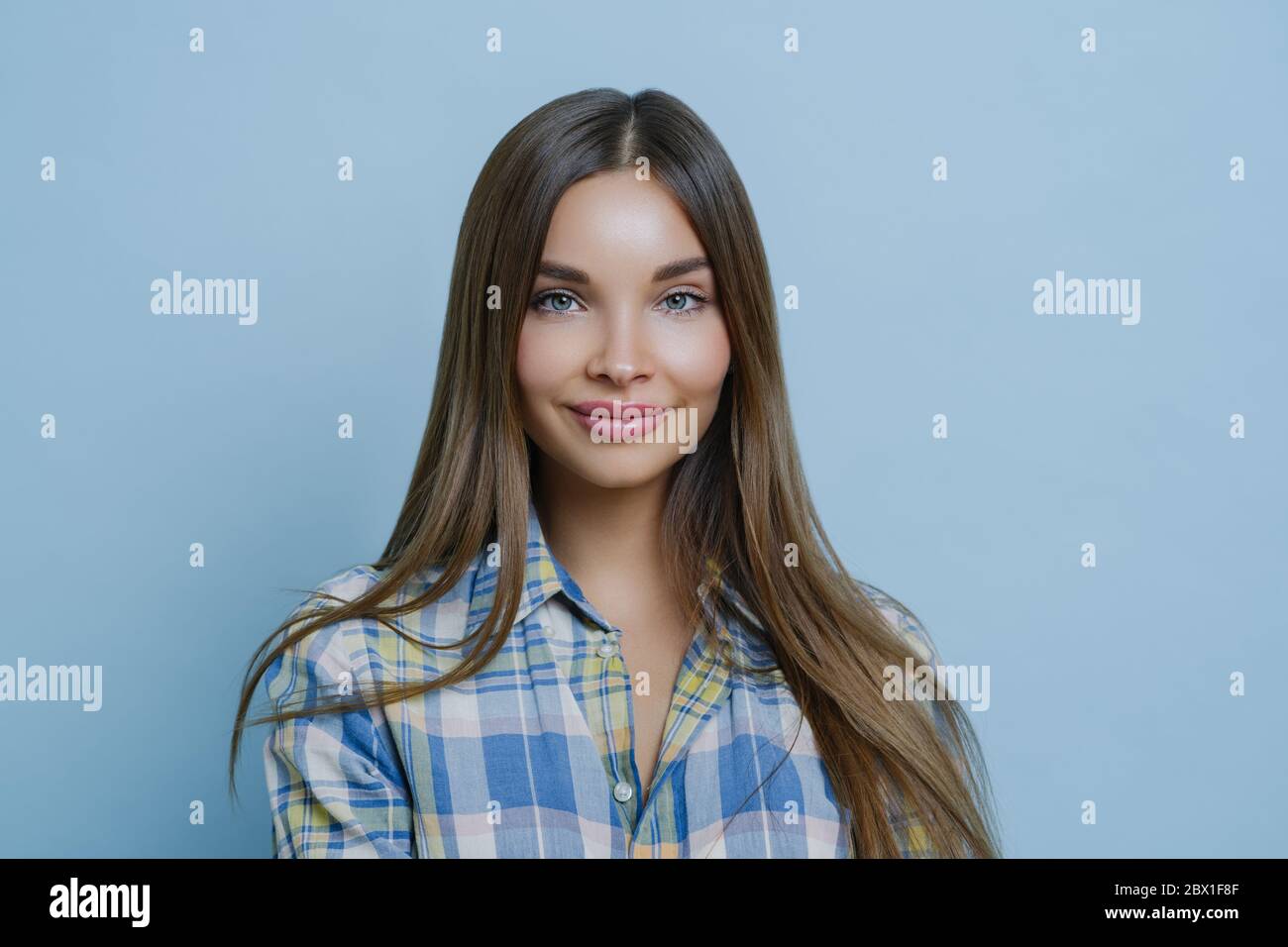 Isolierte Aufnahme von hübschen Geschäftsfrau hat Gesichtsausdruck zufrieden, zartes Lächeln, in lässigen Hemd gekleidet, hat klare Haut und attraktive Gesichtszüge Stockfoto