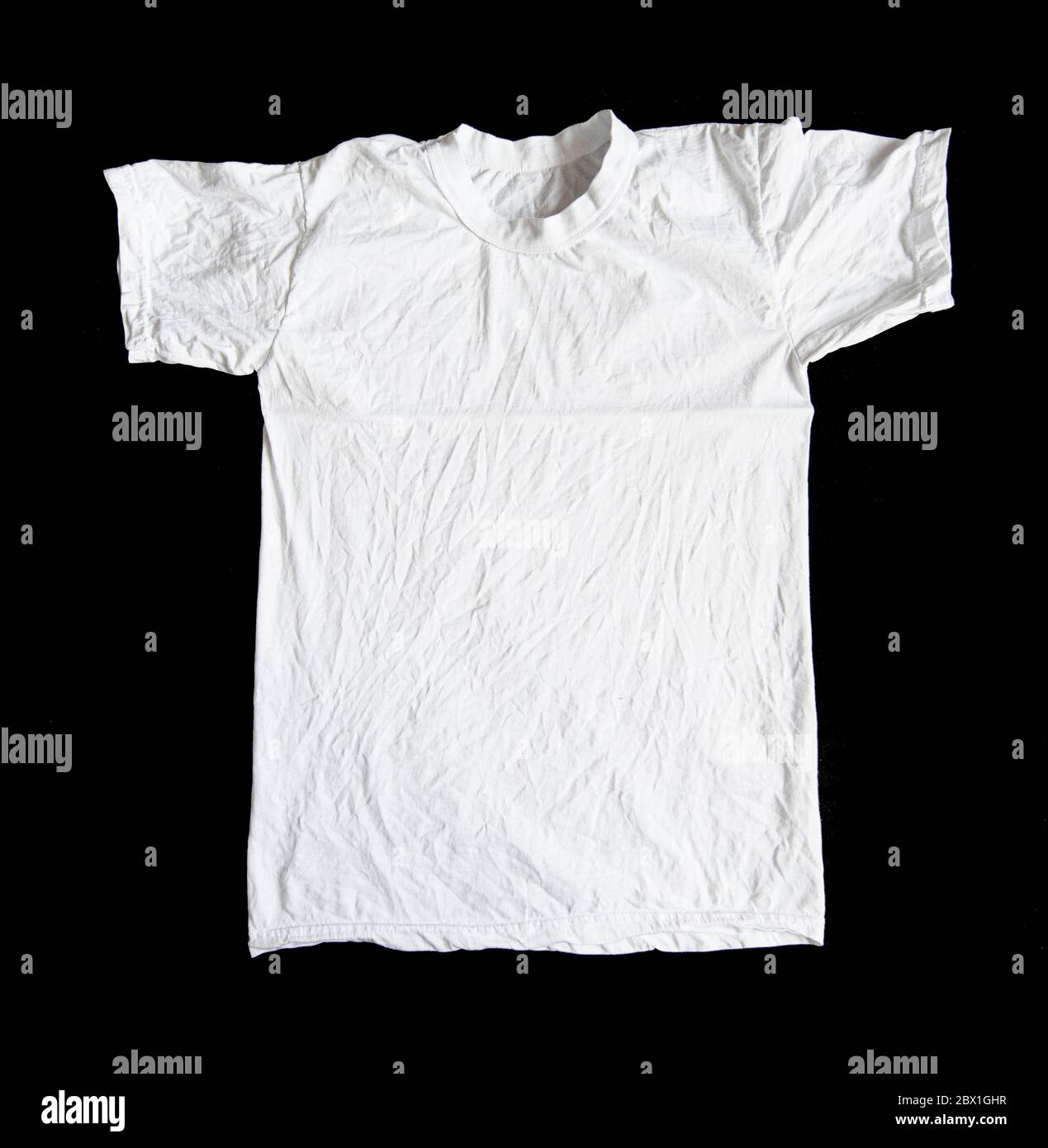 Weißes zerknittertes T-Shirt isoliert auf schwarzem Hintergrund. Faltiges Hemd, Draufsicht. Stockfoto