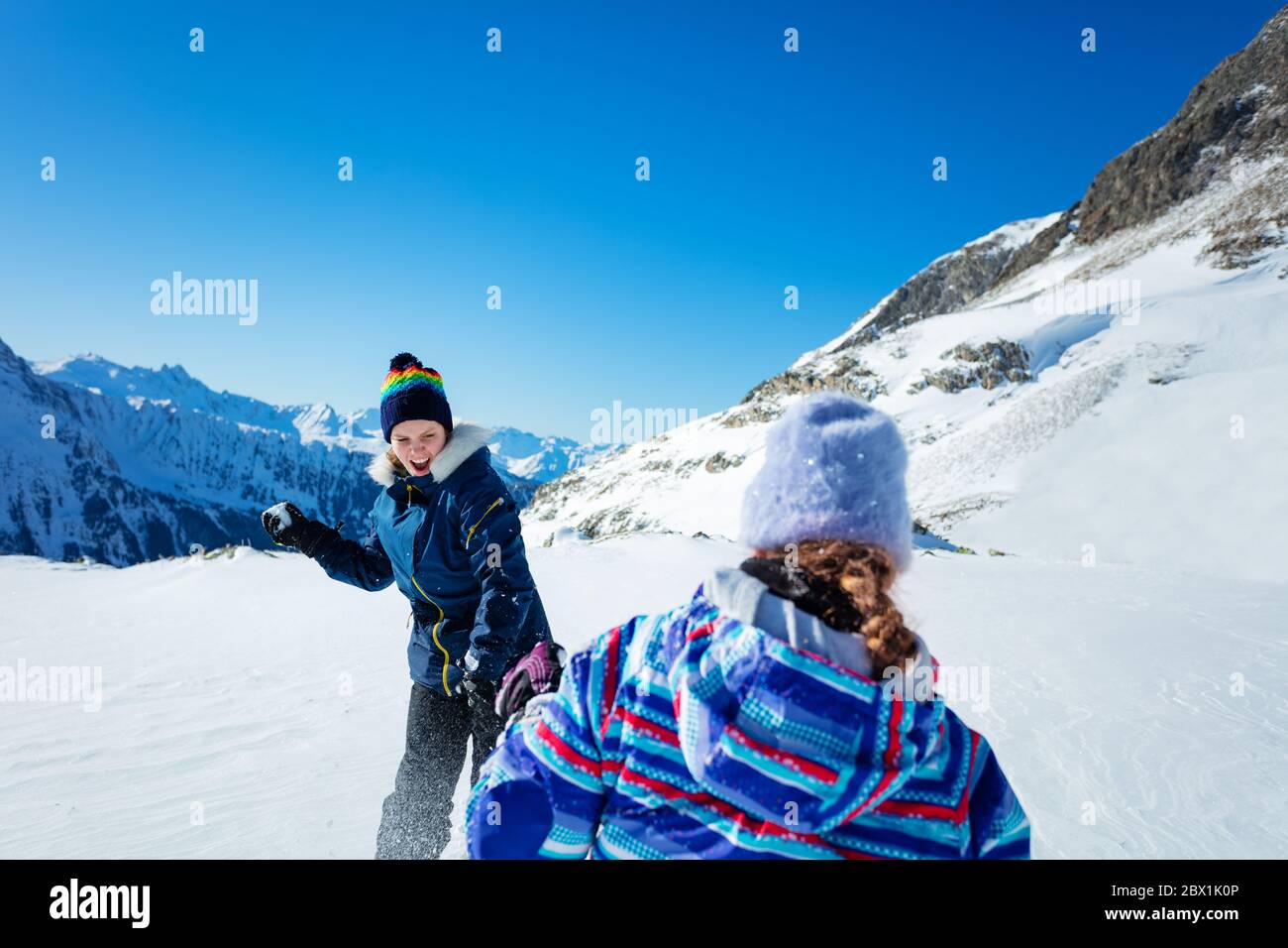 Zwei Mädchen spielen Schneeball Kampf Winter Spiel in den Bergen Schnee werfen und tragen Ski-Outfit Stockfoto