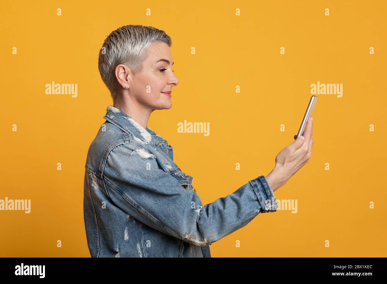 Biometrische Identifizierung. Moderne lächelnde Frau mittleren Alters mit Smartphone-Scan Gesicht in App Stockfoto