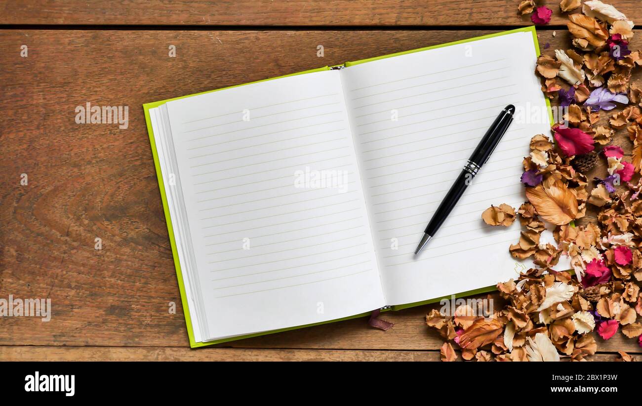 Top-Ansicht Arbeitsbereich mit leerem Notizbuch, Stift und getrockneten Blumen auf Holztisch Hintergrund. Stockfoto