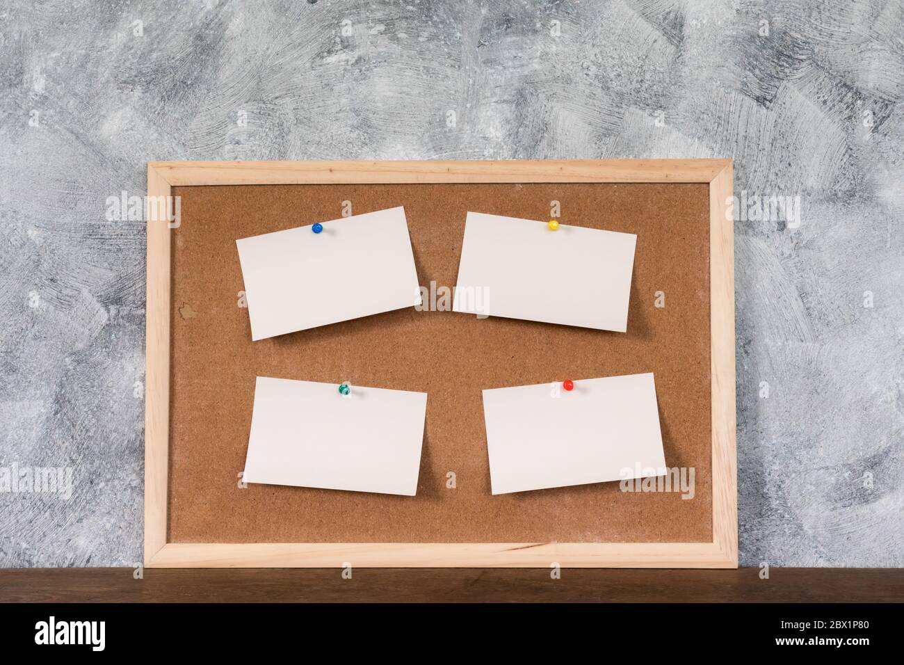 Leere Papiere stecken auf Korkplatte über Holztisch mit texturiertem Hintergrund. Stockfoto