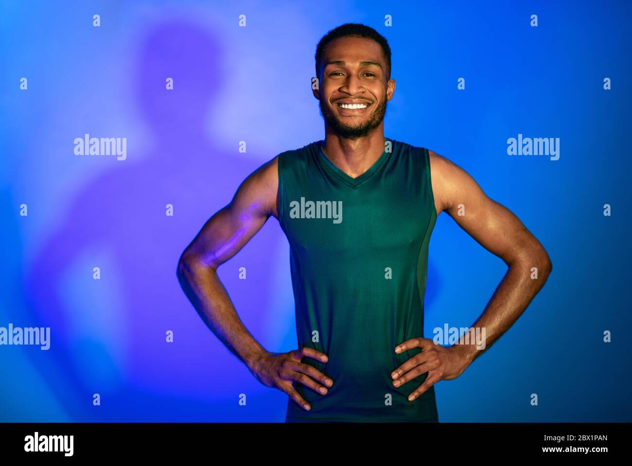 Fröhlicher Athlete Guy In Fitwear Posing Über Blue Studio Hintergrund Stockfoto