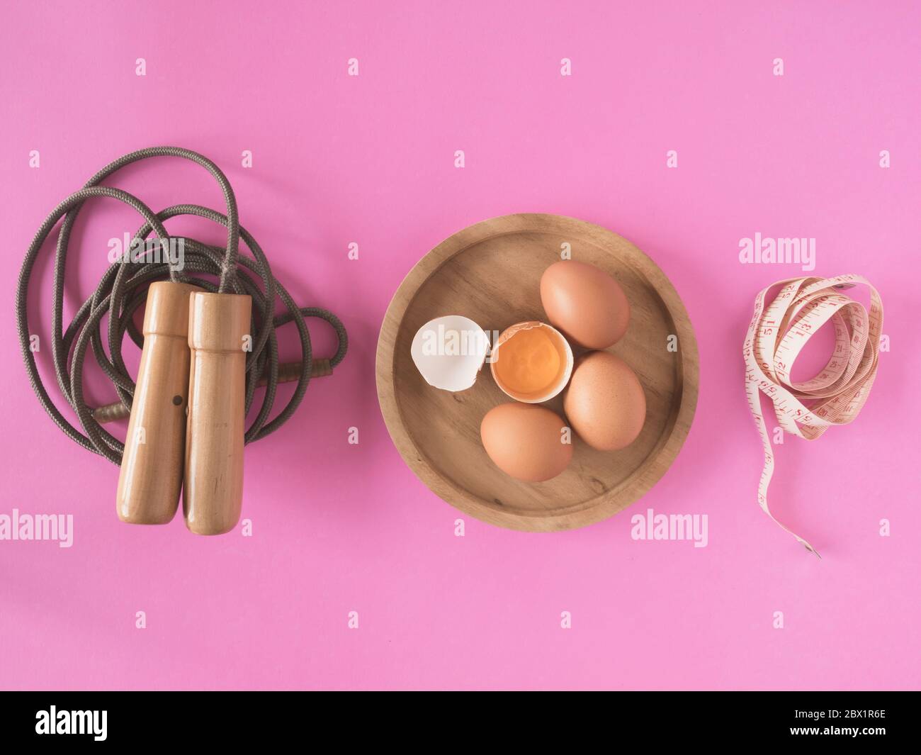 Springseil, Eier und Klebeband messen auf einem rosa Hintergrund. Stockfoto