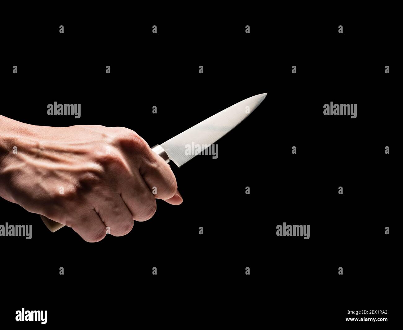 Männliche Hand hält Messer auf schwarzem Hintergrund. Stockfoto