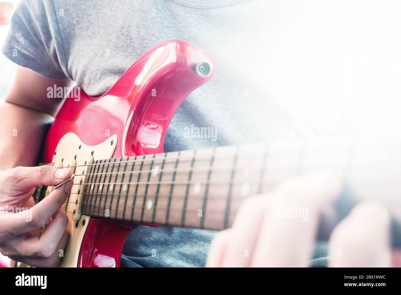 Nahaufnahme von männlichen Händen spielen E-Gitarre, Flare aus dem Sonnenlicht, Selective Focus Stockfoto