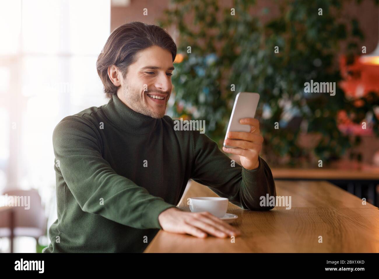 Erfolgreicher Geschäftsmann mit Smartphone während der Kaffeepause Stockfoto