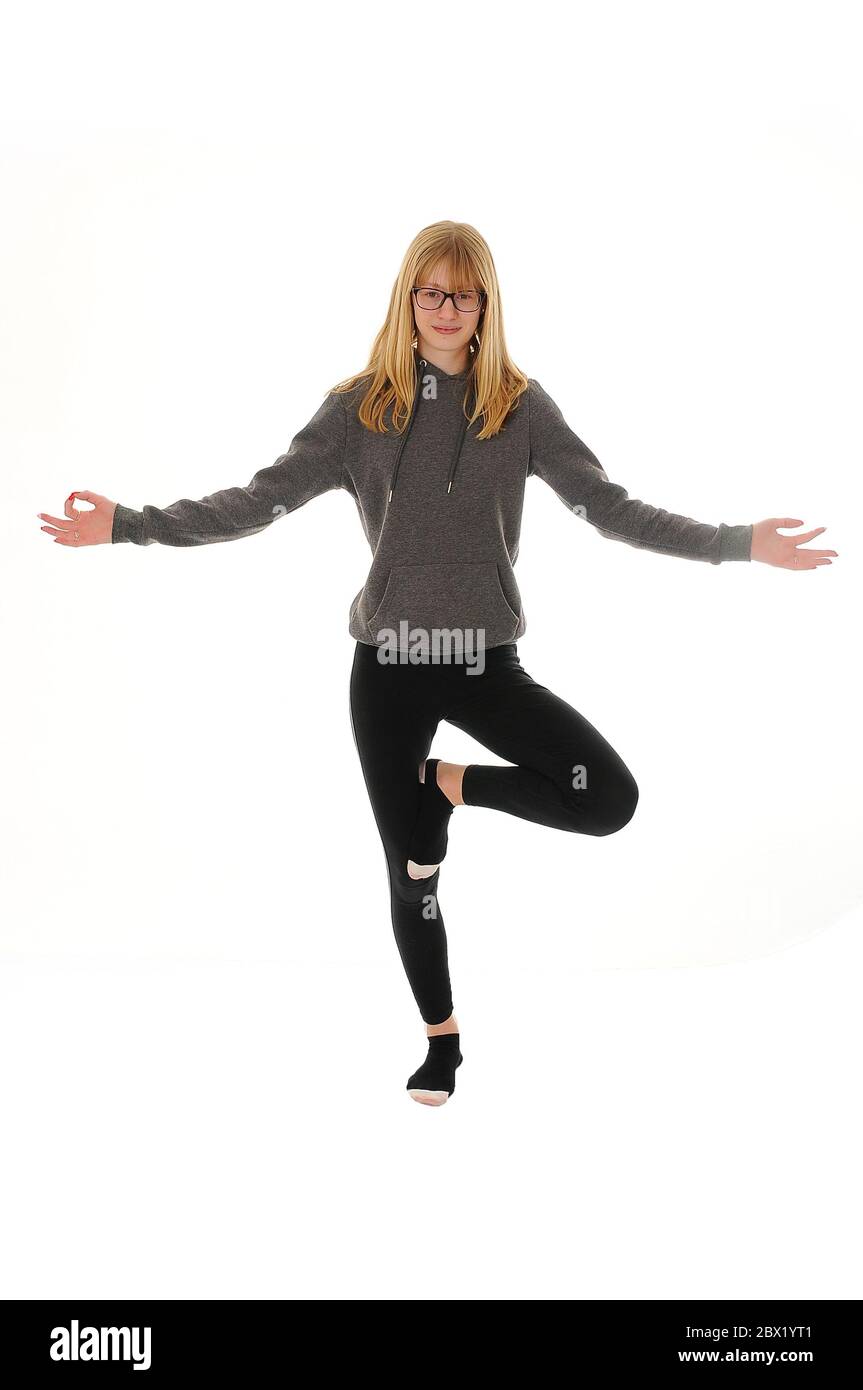 Hübsches blondes Teenager-Mädchen, das auf einem Fuß in einer Yoga-Pose steht, isoliert auf weißem Hintergrund Stockfoto