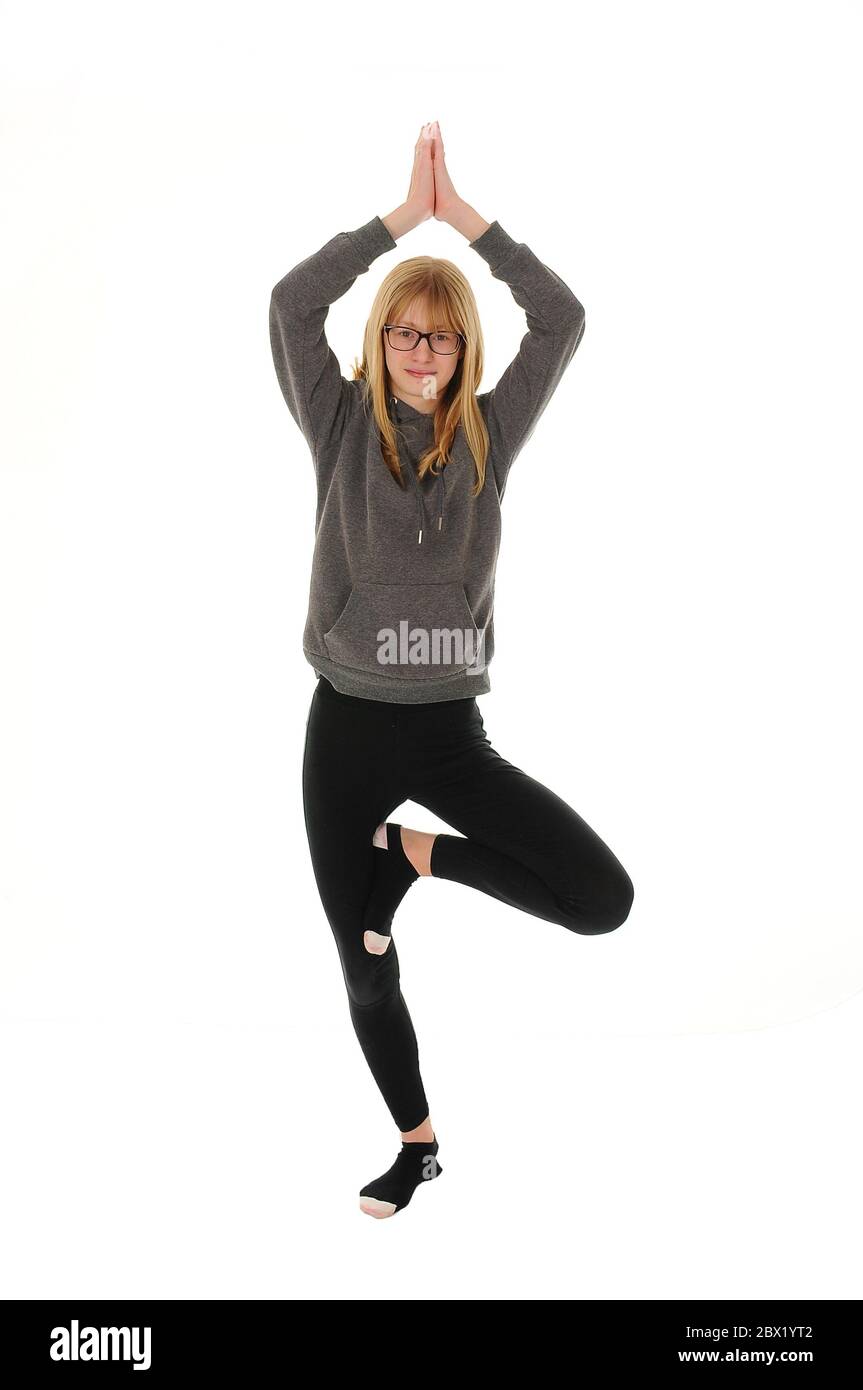 Hübsches blondes Teenager-Mädchen, das auf einem Fuß in einer Yoga-Pose steht, isoliert auf weißem Hintergrund Stockfoto