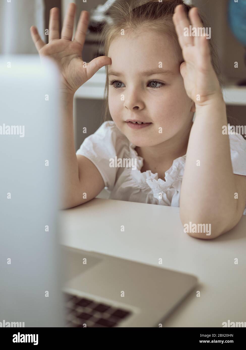 Nettes kleines Mädchen mit Laptop zu Hause. Bildung, Online-Studium, Zuhause das Mädchen zu Hause kommuniziert mit Freunden im Internet. Kinder Fernunterricht. Hochwertige Fotos Stockfoto