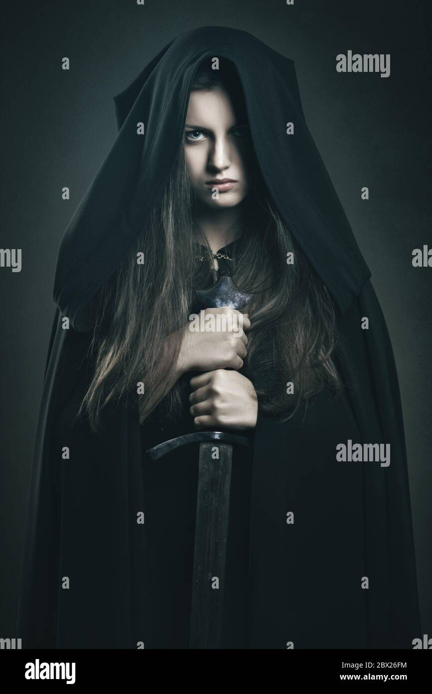 Schöne dunkle Frau mit schwarzer Robe und Schwert. Fantasie und Legende Stockfoto