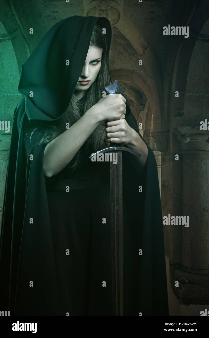 Schöne Frau mit Schwert in einem Steinschloss. Fantasie und Legende Stockfoto