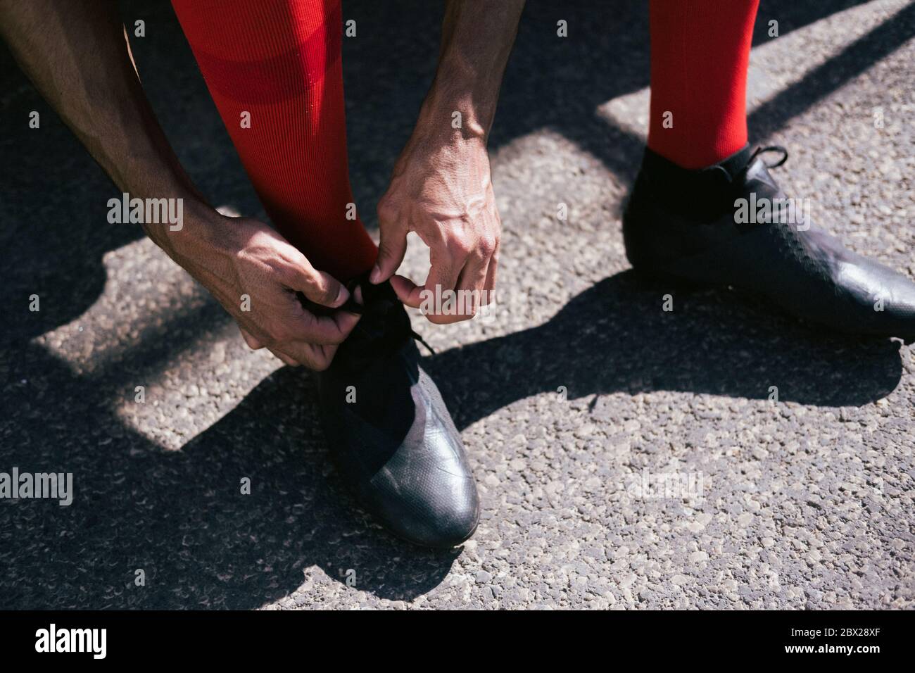 Nahaufnahme der Füße des Fußballspielers, die seine Stiefel fixieren Stockfoto