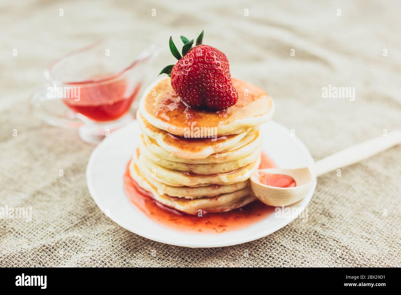 Kinderdelikatesse - frisch heiße süße Pfannkuchen mit Erdbeermarmelade zum Frühstück - Tee trinken Stockfoto