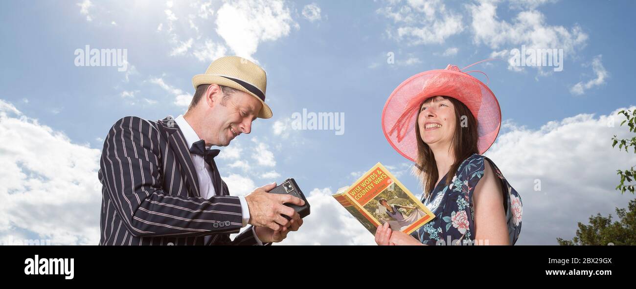 Low Angle Nahaufnahme von Großbritannien glückliches Paar im Vintage 1940s Kostüm im Freien im Sommer Sonnenschein. Mann fotografiert Frau mit Vintage Box Brownie Kamera. Stockfoto