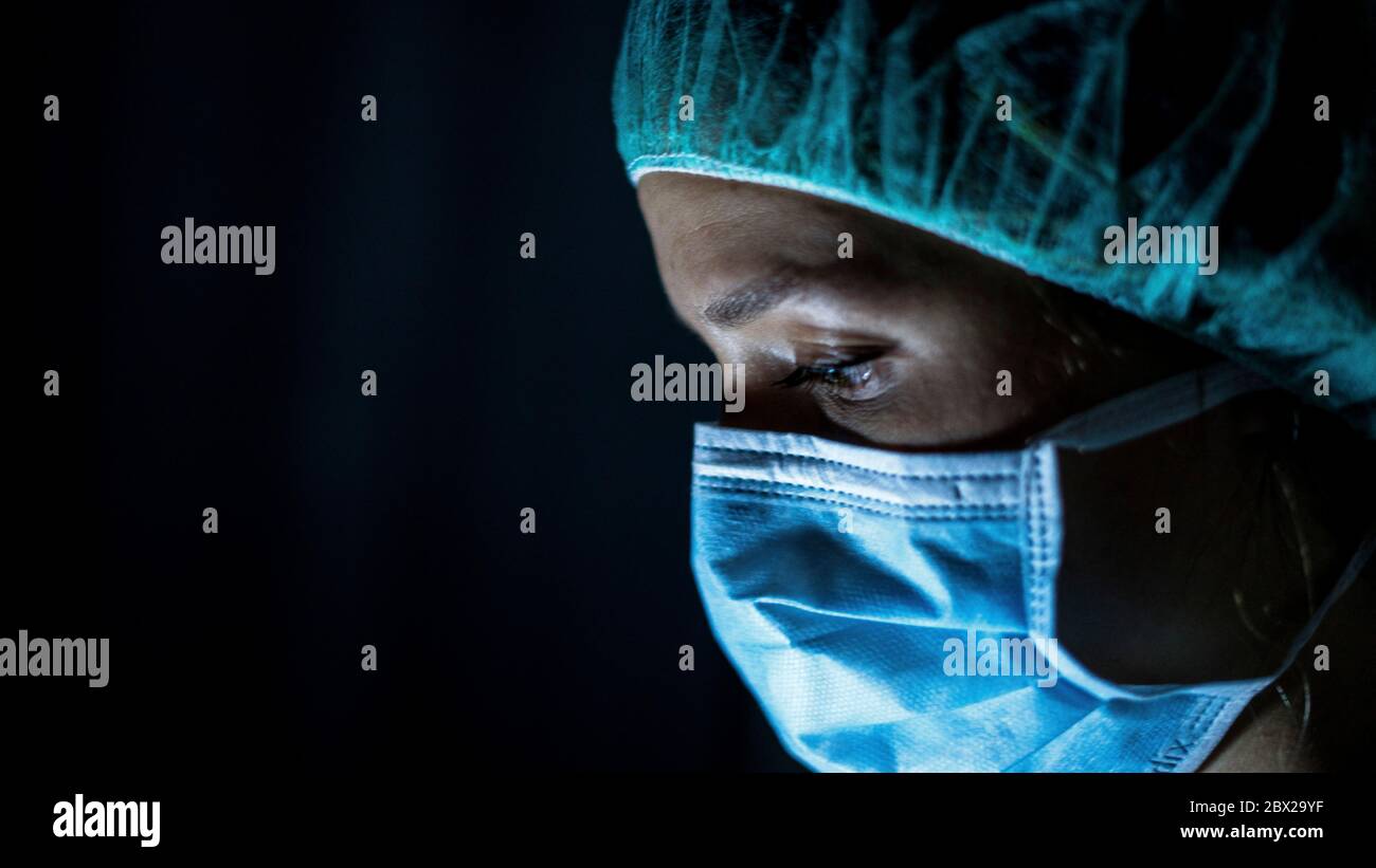 Porträt einer jungen Chirurgen, Maske und eine OP-Maske, vor schwarzem Hintergrund Stockfoto