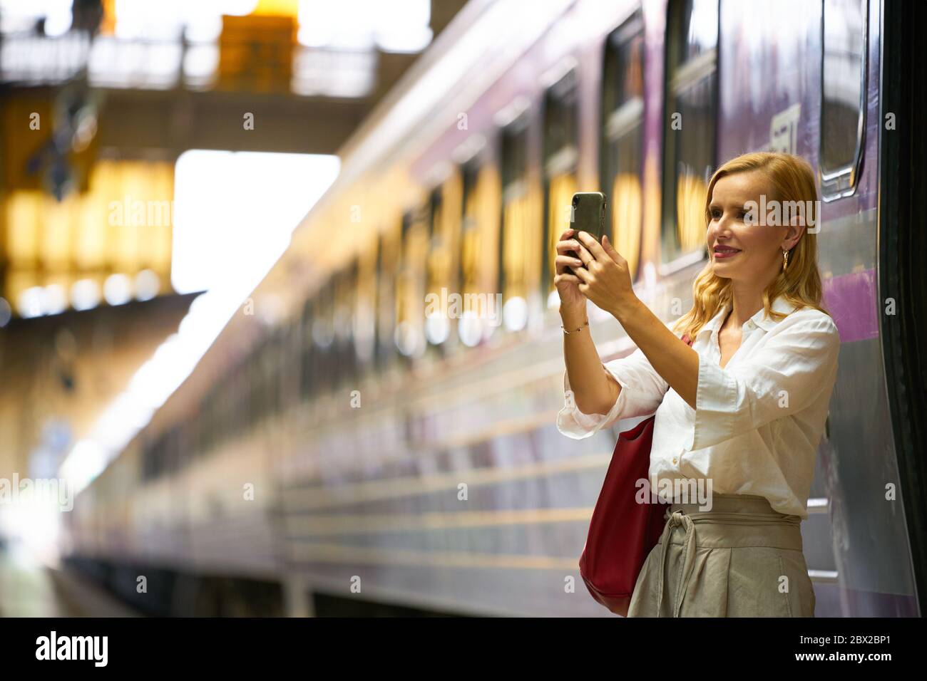 Eine Frau, die mit einem iPhone im Bahnhof von Bangkok fotografiert Stockfoto