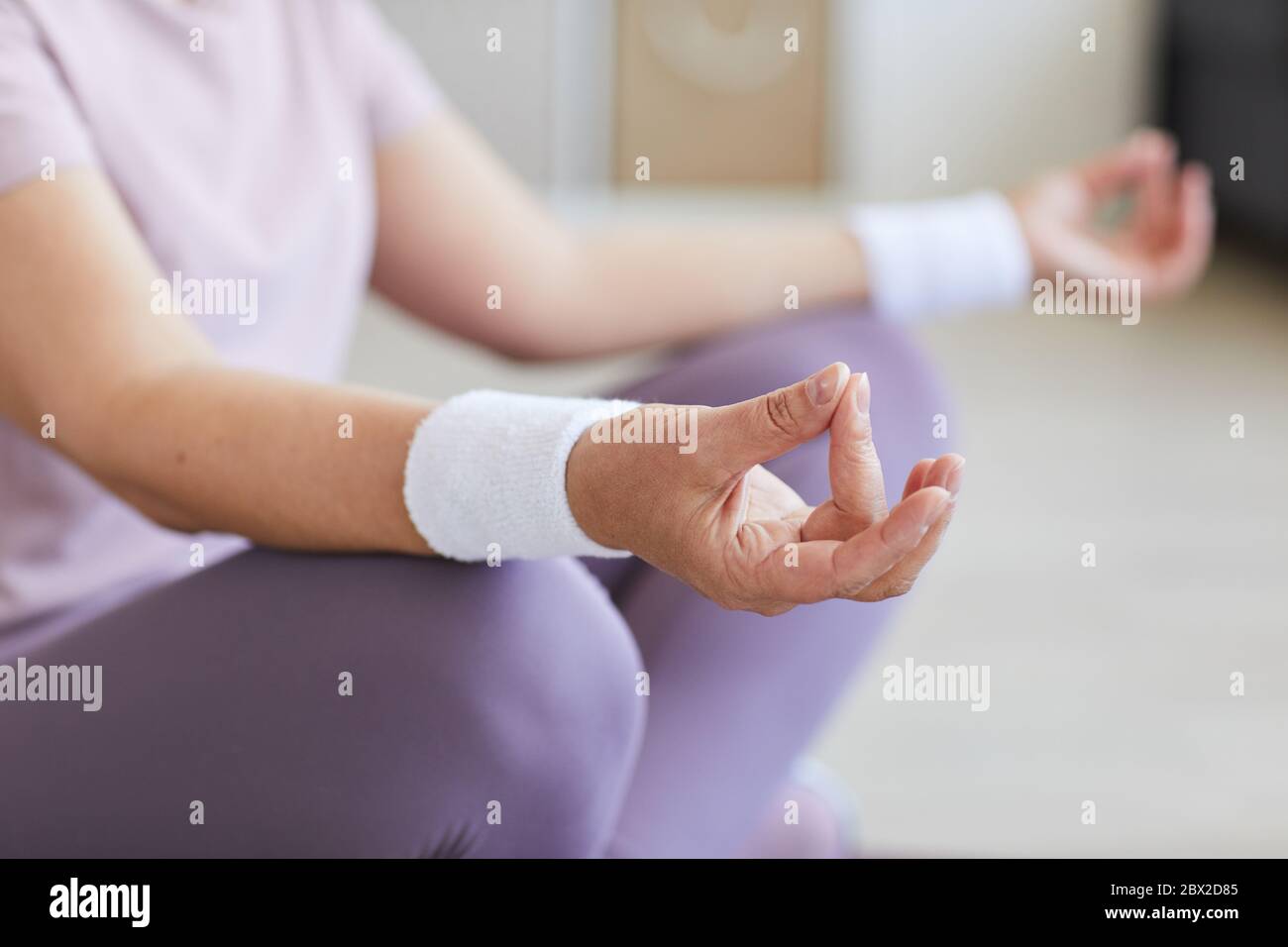 Nahaufnahme einer älteren Frau, die in Lotusposition sitzt und meditiert Stockfoto