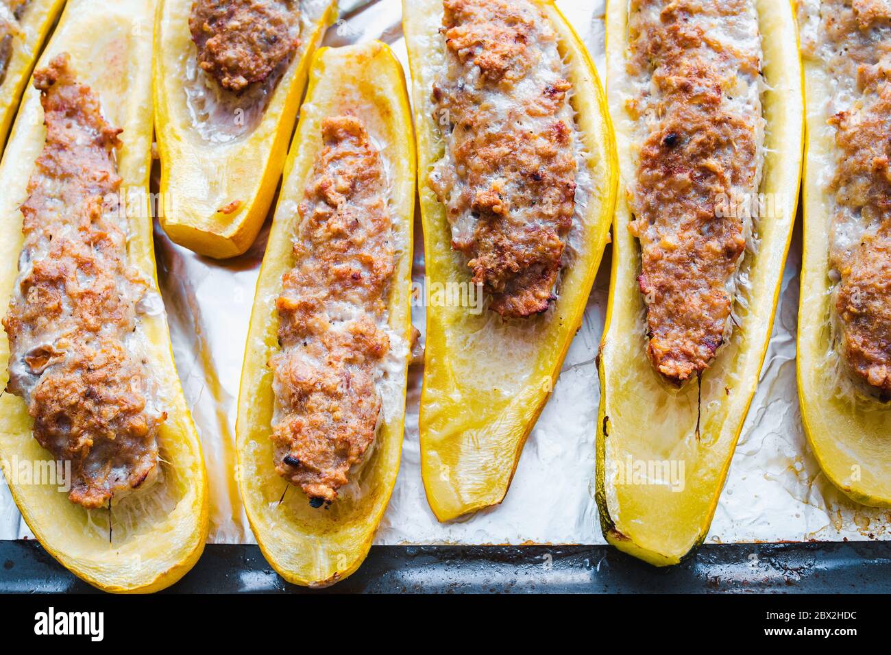 Zucchini in Scheiben geschnitten, gefüllt mit Hackfleisch auf einem Backblech Stockfoto