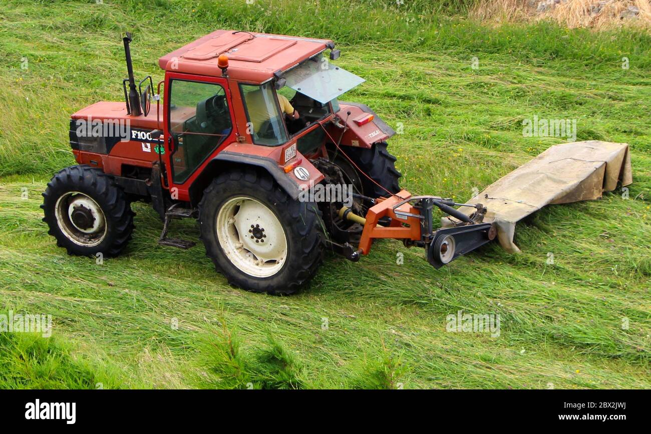 Milchviehtraktor mit Schlepplift hinter dem Scheibenmäher zum Schneiden von Gras Santander Cantabria Spanien Stockfoto