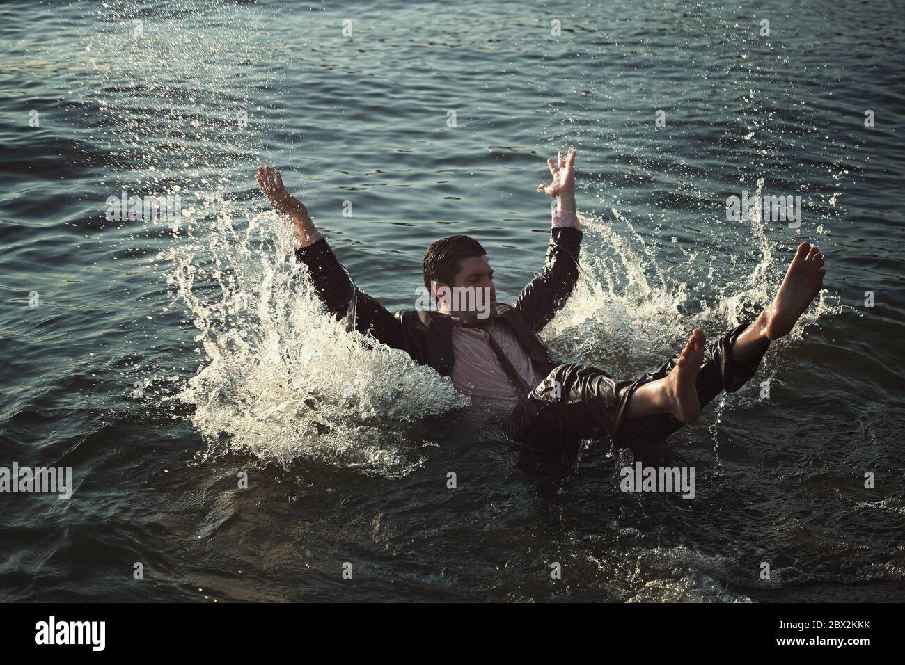 Junger Mann, der mit Business-Anzug im Meer schwimmend. Müde von der Arbeit Stockfoto