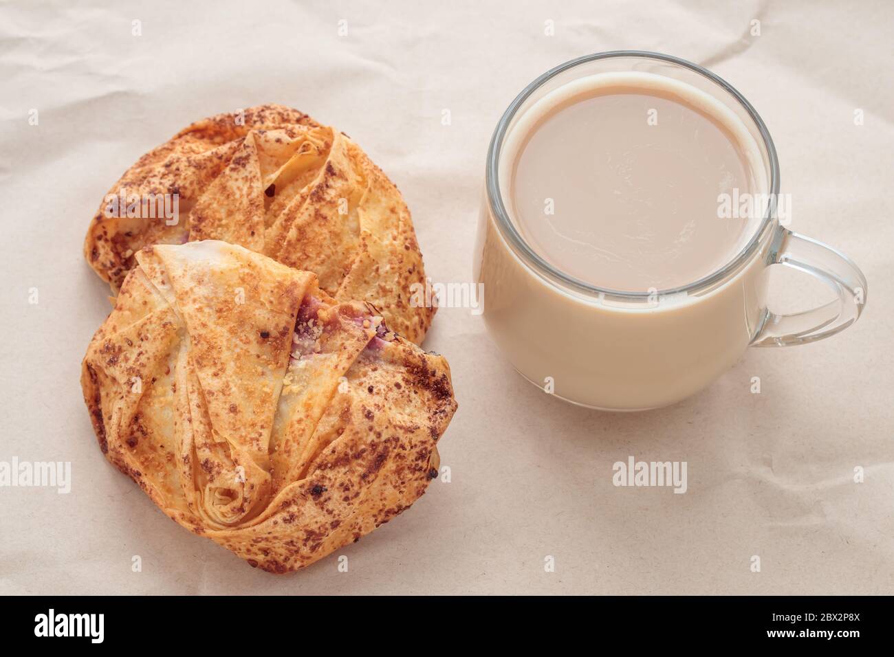 Tasse Kaffee und Scones auf braunem, zerknittertem Papier. Frühstückskonzept Stockfoto