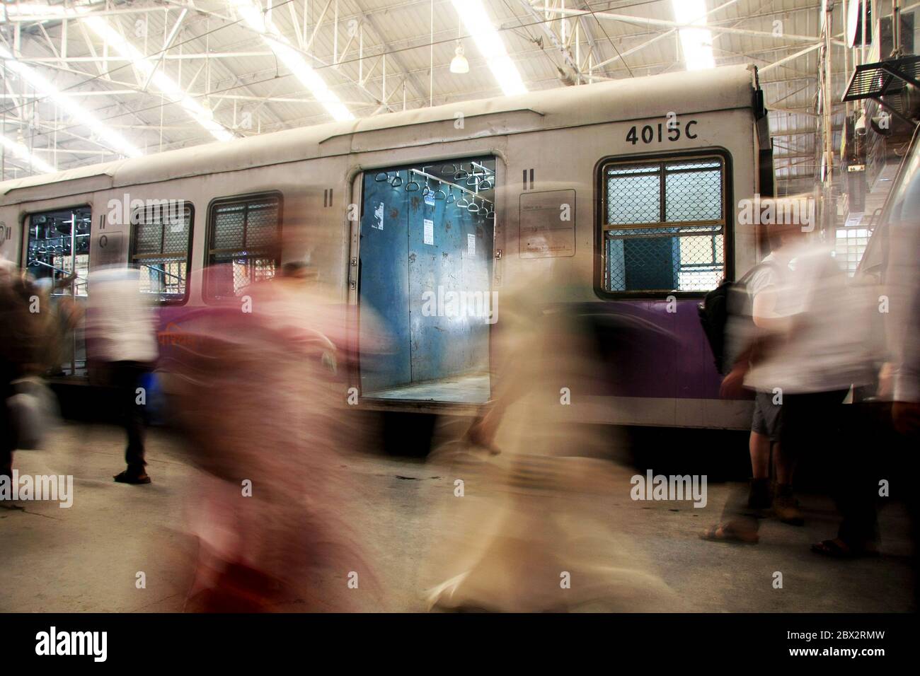 Bewegungsunschärfe von Menschen, die sich täglich auf dem Weg zur Arbeit in Indien bewegen, mit einem Zug im Hintergrund Stockfoto