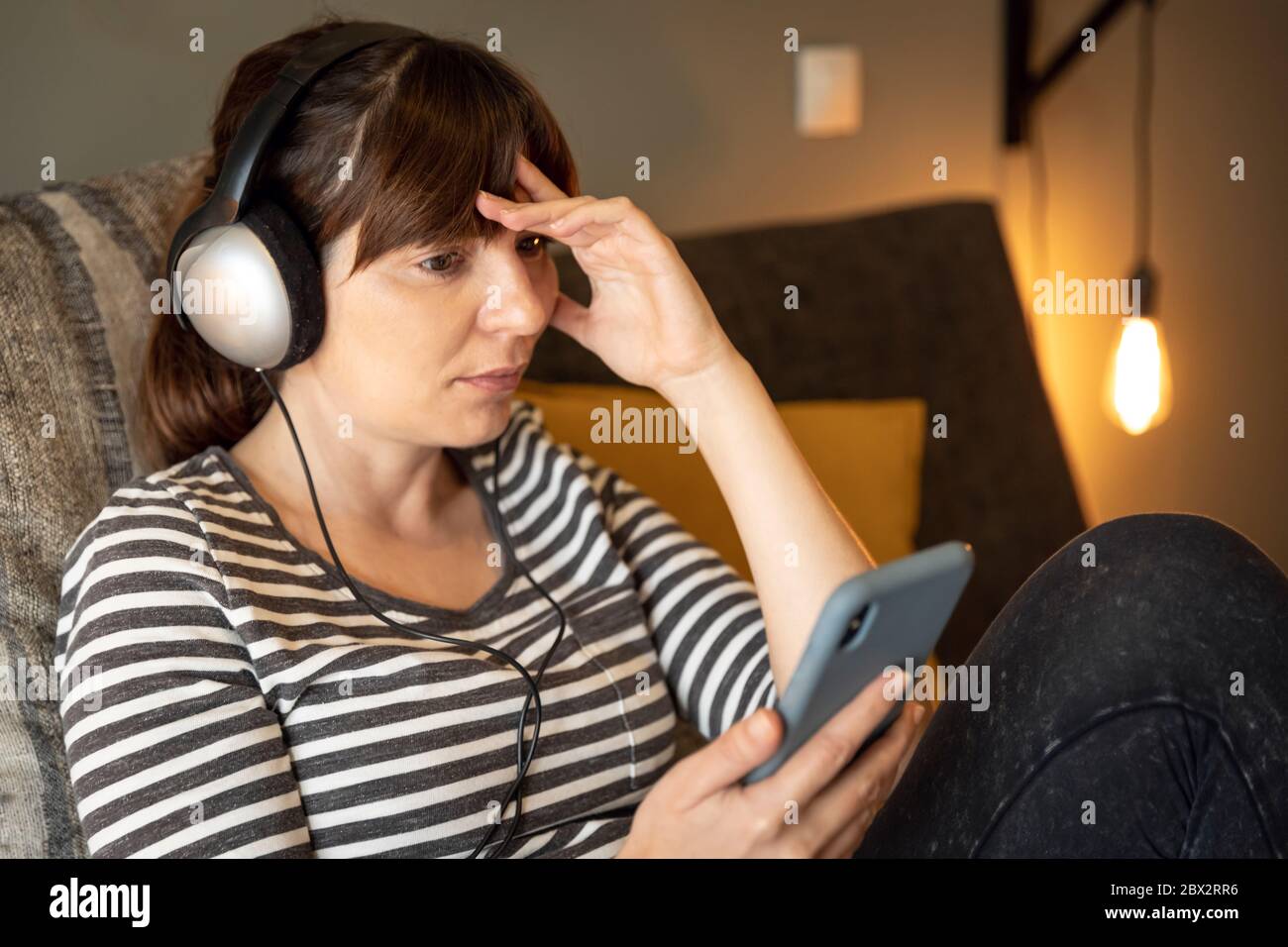 Frau am Telefon im Bett mit Symptomen einer Depression Stockfoto