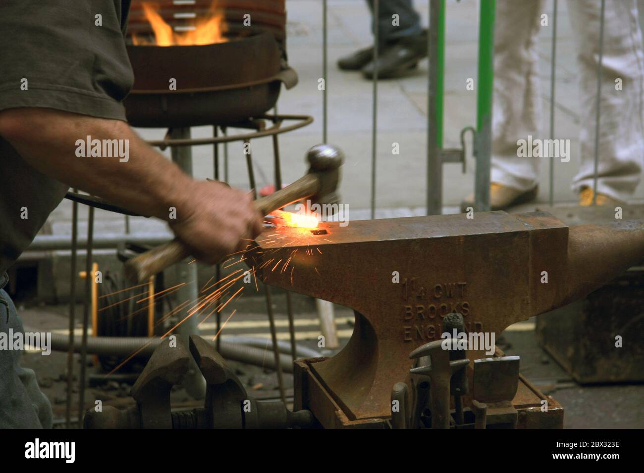 Metallbearbeitung - Mann schlägt beheizte Stahlstange mit einem Hammer auf einem traditionellen Eisenanvil (Schmied) Stockfoto