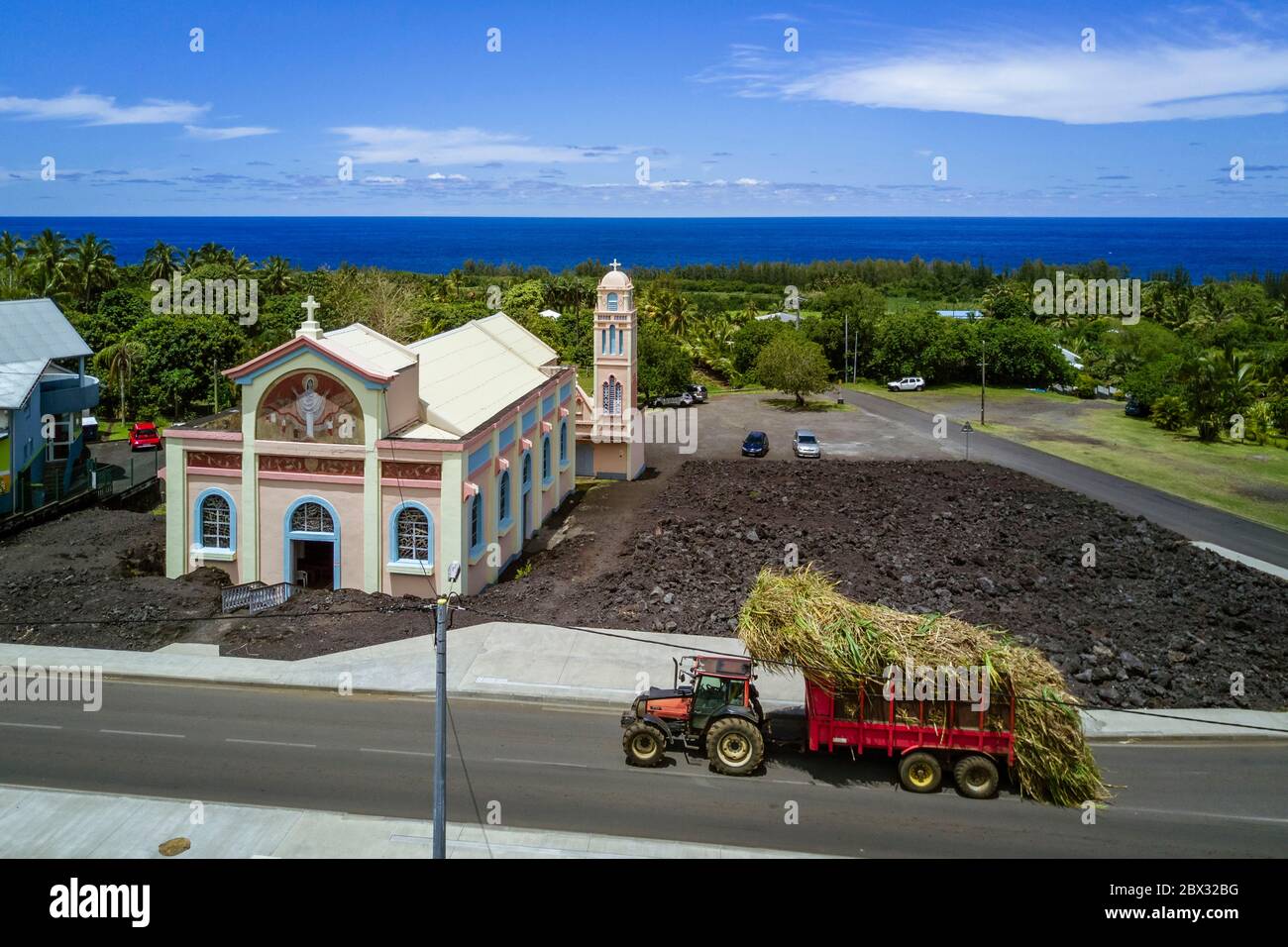 Frankreich, Réunion Island (Französisch Übersee-Department), die Notre-Dame-des-Laves Kirche von Piton Sainte-Rose verschont durch den Lavastrom von 1977, Traktor mit einer Ladung Zuckerrohr zur Zuckerfabrik (Luftaufnahme) Stockfoto