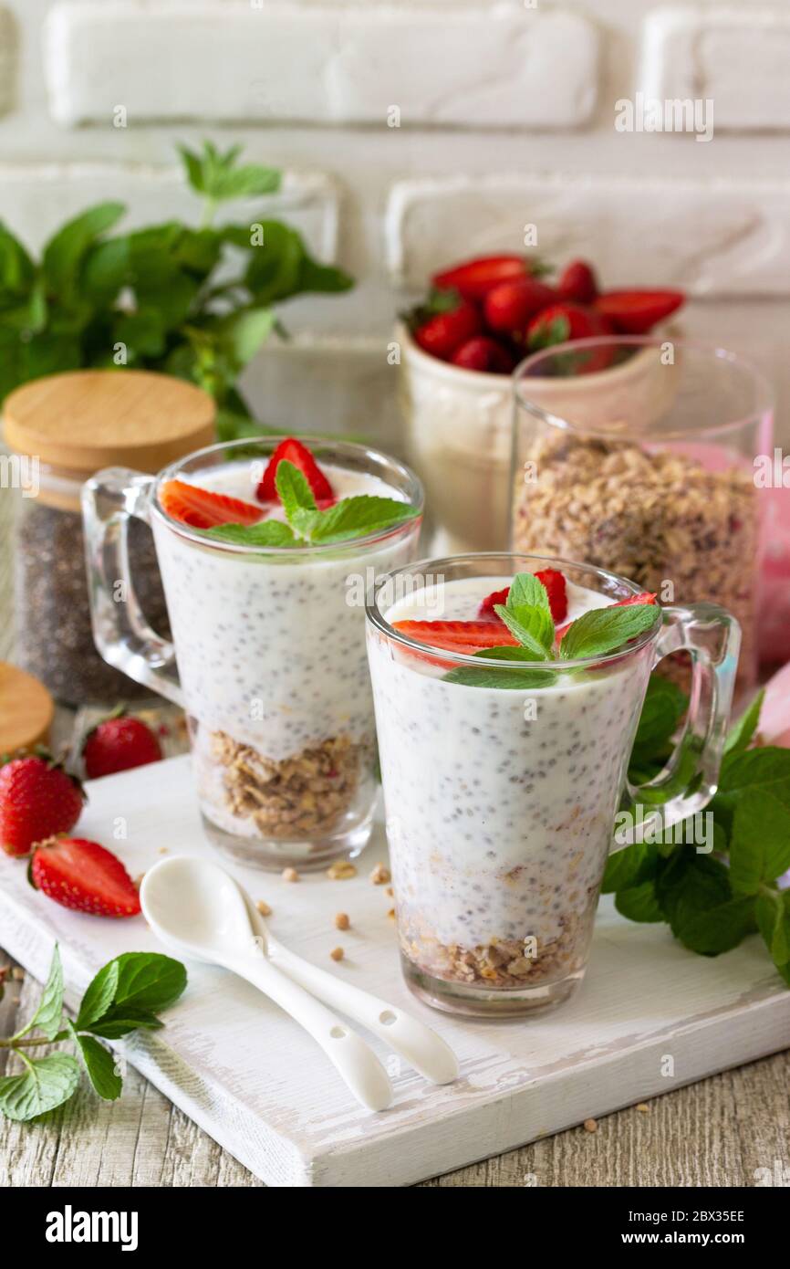 Gesundes Essen Konzept Frühstück. Erdbeerparfait mit Joghurt, Chiasamen, hausgemachtem Müsli und frischen Beeren auf einer Steinbetonarbeitspfläche. Stockfoto