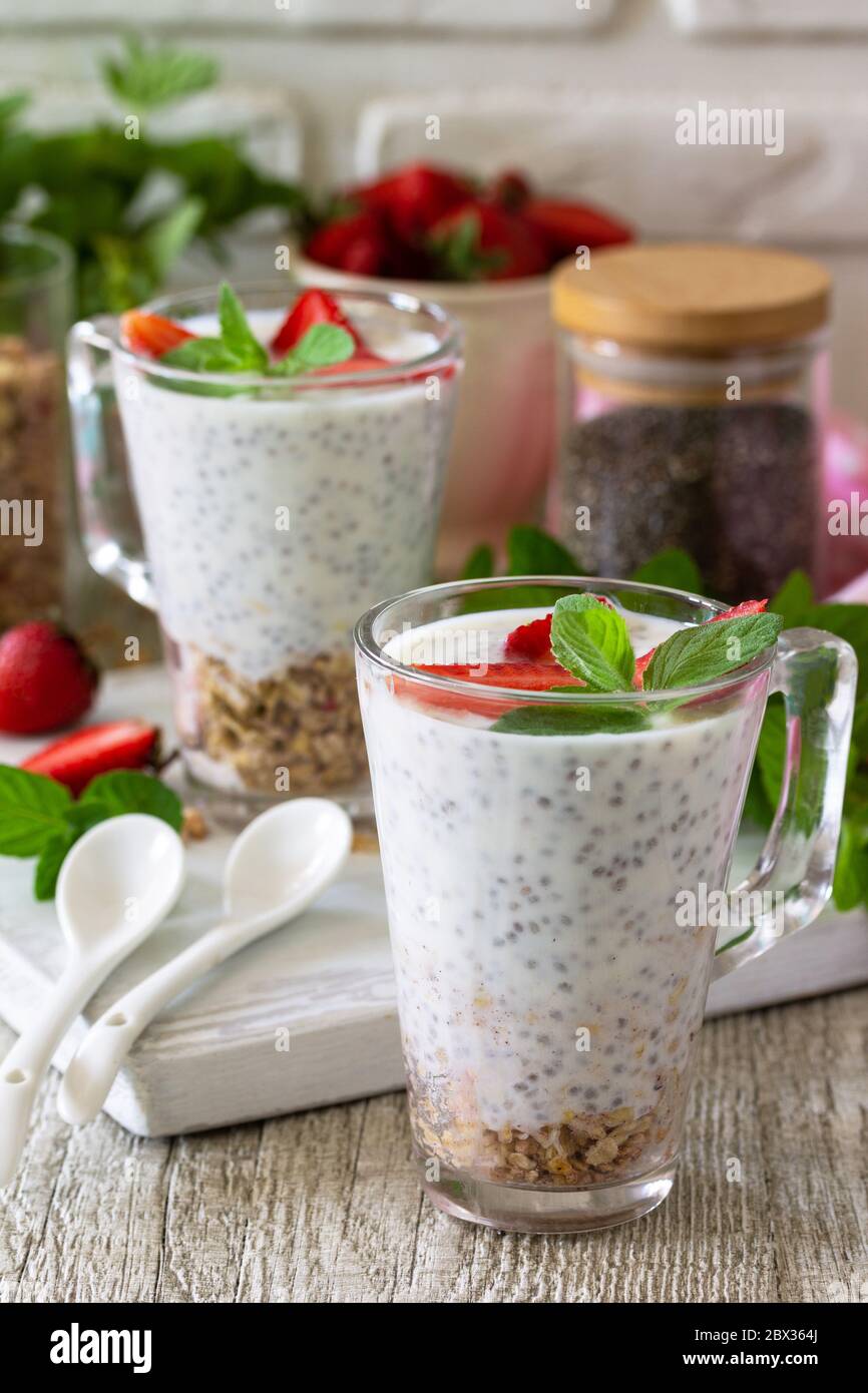 Gesundes Essen Konzept Frühstück. Erdbeerparfait mit Joghurt, Chiasamen, hausgemachtem Müsli und frischen Beeren auf einer Steinbetonarbeitspfläche. Stockfoto