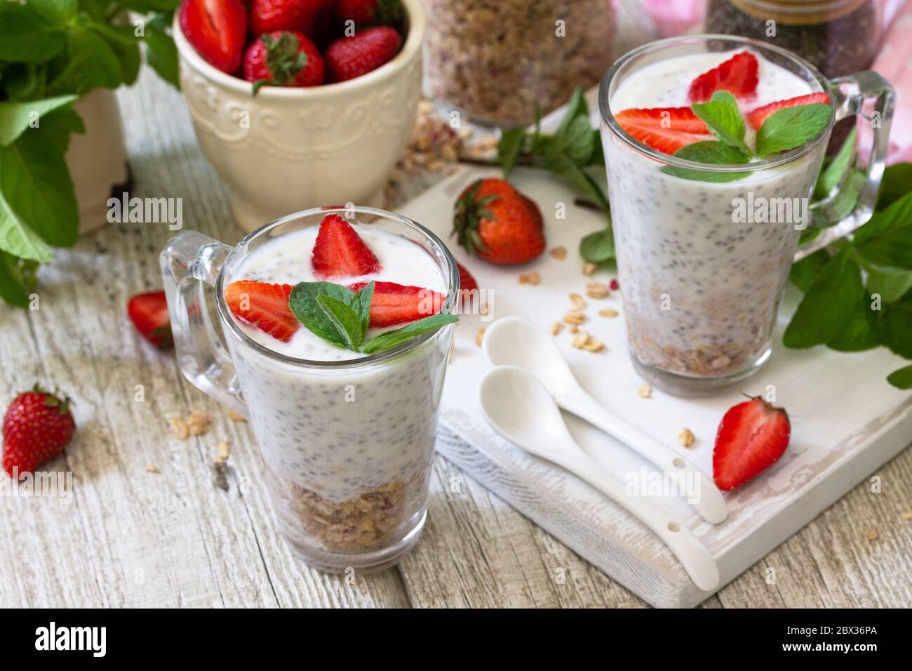 Gesundes Essen Konzept Frühstück. Erdbeerparfait mit Joghurt, Chiasamen, hausgemachtem Müsli und frischen Beeren auf einer Steinbetonarbeitspfläche. Stockfoto
