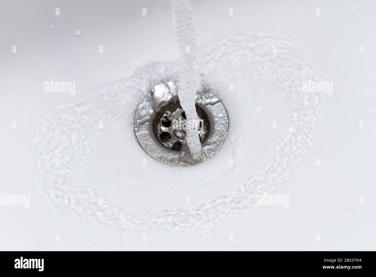 Wasser fällt in Zeitlupe in die Spüle, Abfluss Nahaufnahme Stockfoto