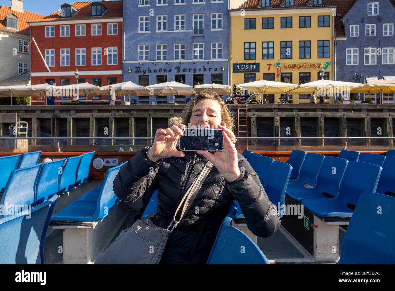 Frau, die Fotos auf einem Smartphone von EINER Kopenhagener Kanalboottour auf einer Tour durch die Kanäle von Kopenhagen Dänemark von Nyhavn Waterfront Stockfoto