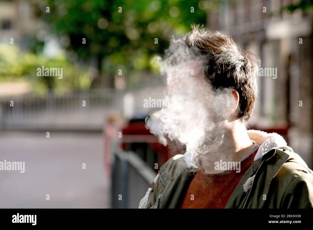 Das Gesicht eines Mannes, der vollständig von dickem Zigarettenrauch bedeckt ist Stockfoto