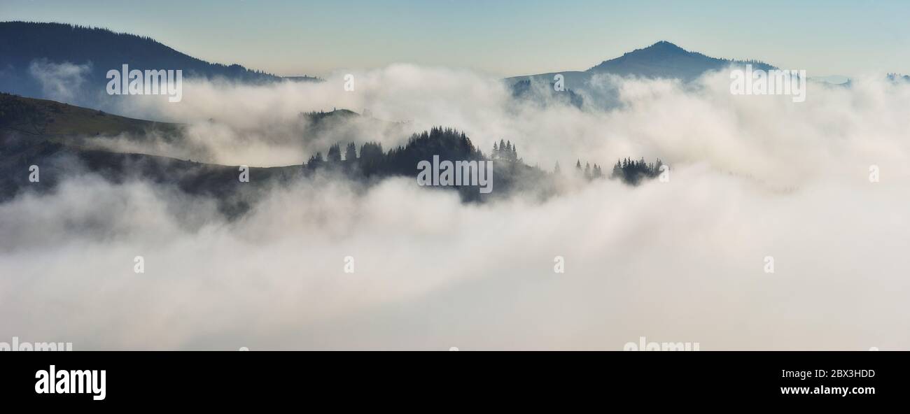 Vordämmerungszeit im Hochland. Bergsilhouetten im Nebel Stockfoto