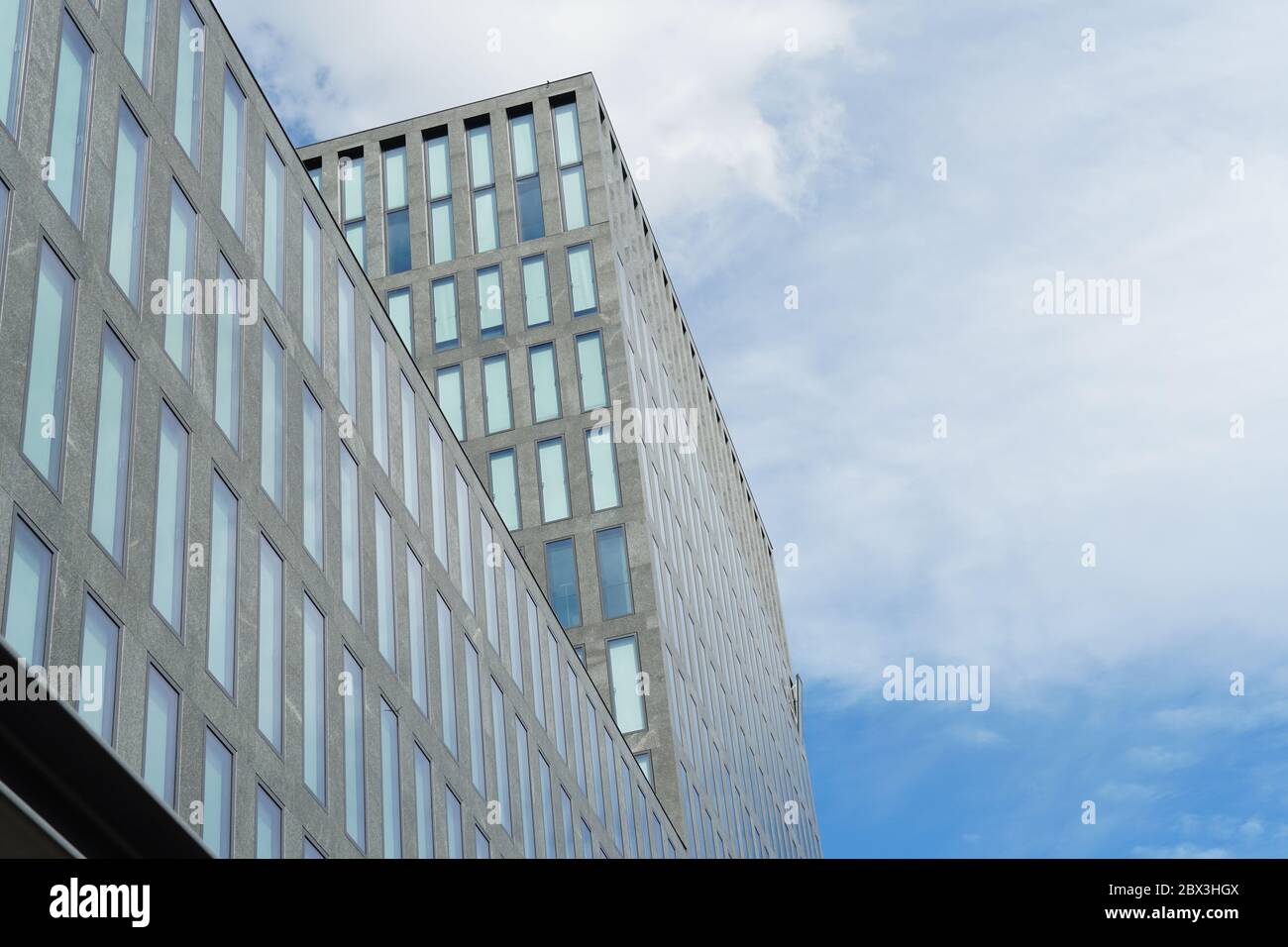 Fassade eines modernen Firmengebäudes mit rechteckigen Fenstern. Es ist nur ein Fenster geöffnet, das aus der einheitlichen Fassade als Symbol für einzigartig hervorwölbt Stockfoto