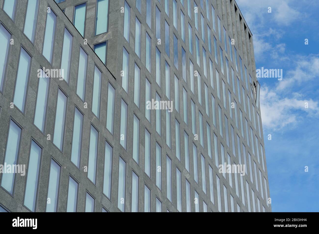 Ein einziges offenes Fenster, das aus einer einheitlichen Fassade eines Unternehmensgebäudes hervorwölbt. Ein Symbol für einzigartige, außergewöhnliche, außergewöhnliche Situation oder Ereignis. Stockfoto