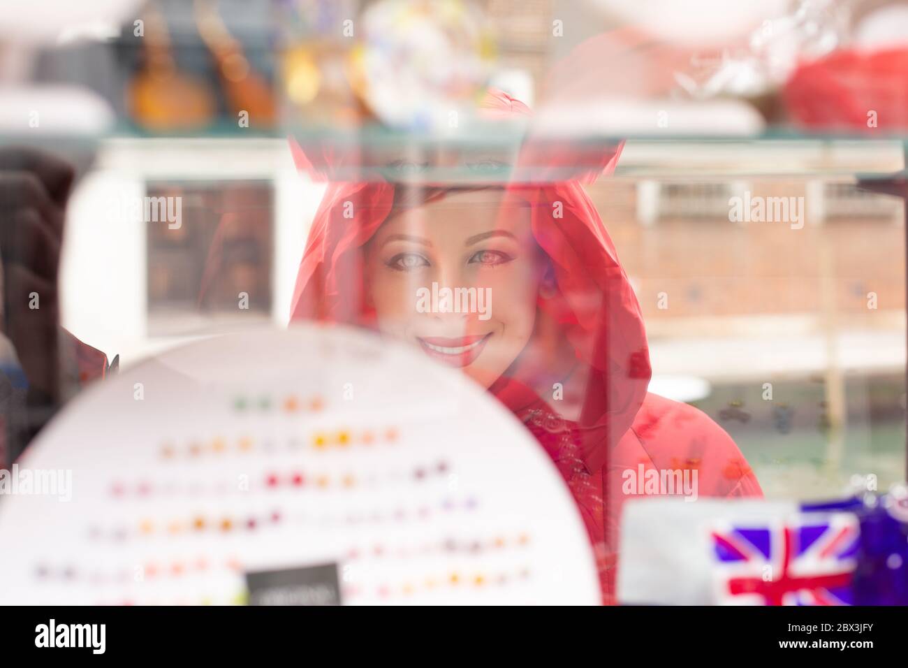 Seite Profil Frau lächelnd auf Bijouterie im Schaufenster in Italien auf der Insel Murano. Dame in rot Winter Mantel Kleidung redhead Haare stehen auf Stockfoto