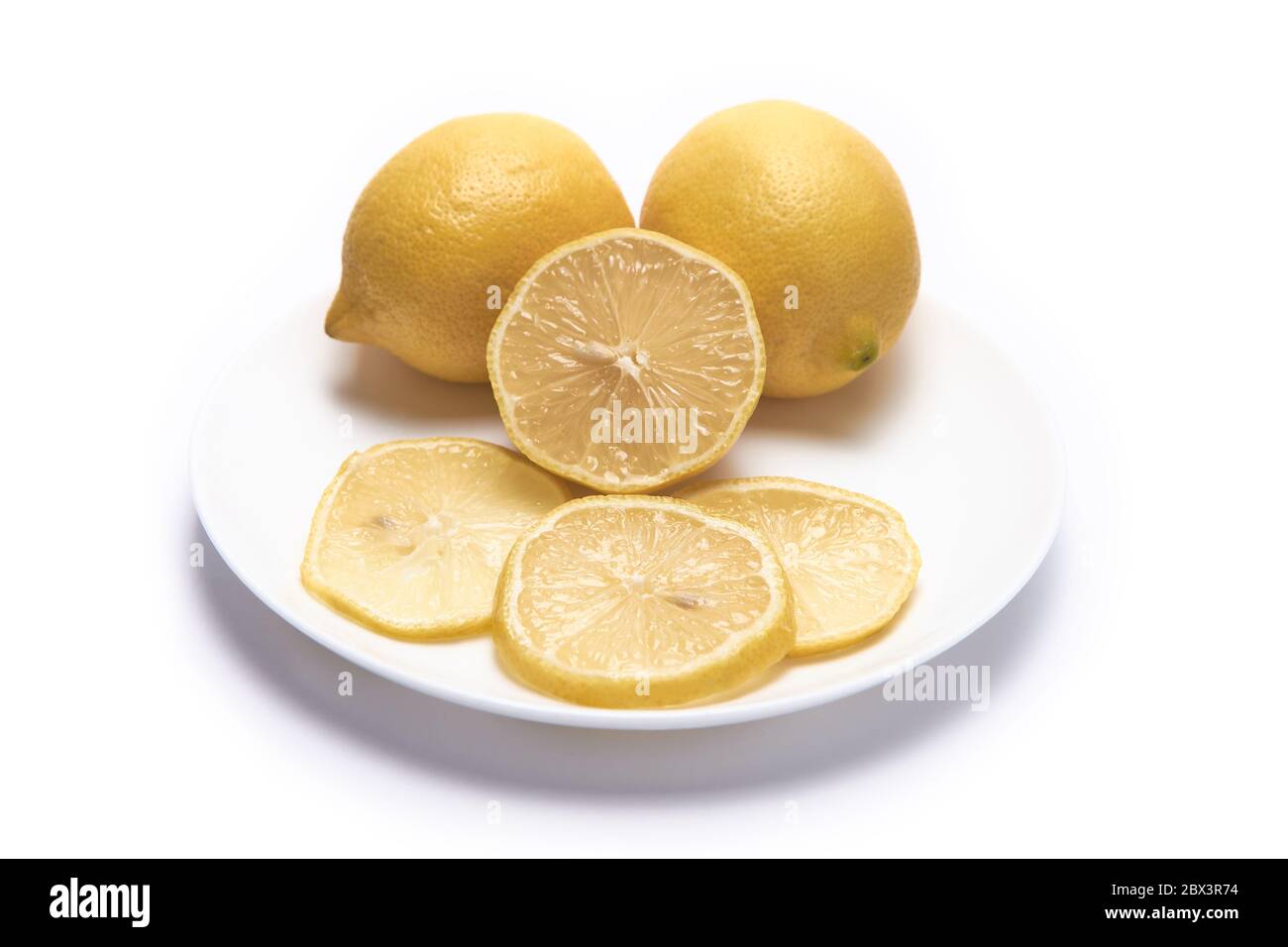 Zweieinhalb Zitronen und einige Scheiben auf weißem Hintergrund nehmen die ganze Szene auf Stockfoto