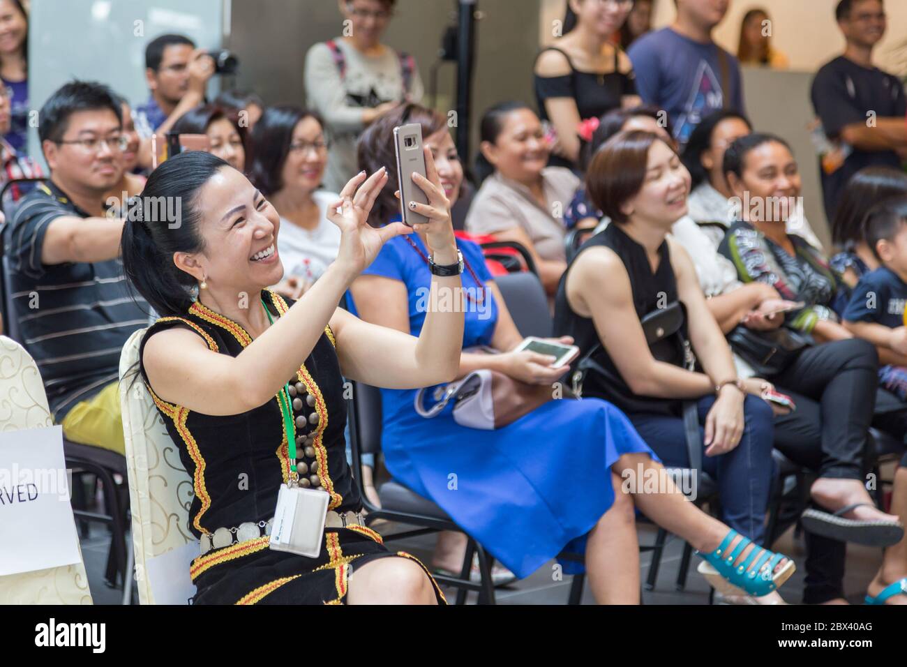 Kota Kinabalu, Sabah , Malaysia - 22. Mai 2017 : EINE Dame in traditioneller Tracht mit Halten des Telefons mit Capture einige Bilder Stockfoto