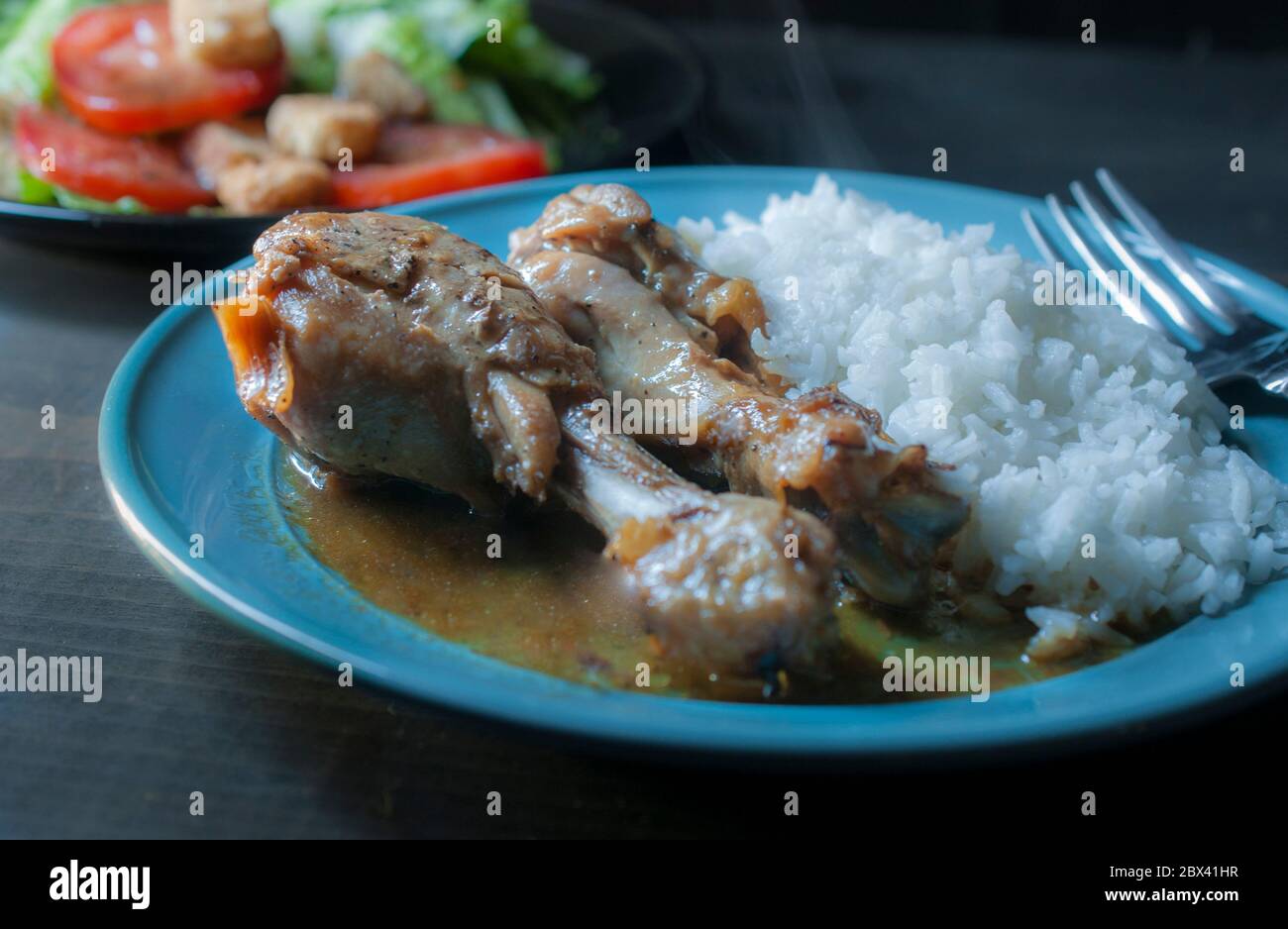 Hausgemachte Hähnchenbeine mit Austernsauce und Dampf Reis mit einem Teller mit frischem Salat im Hintergrund Stockfoto