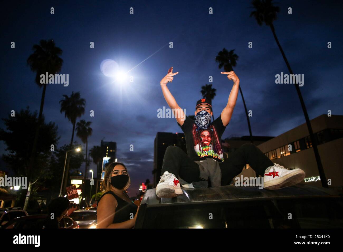 Los Angeles, Usa. Juni 2020. Ein Protestler hebt zwei Mittelfinger in die Luft und zeigt auf einen Polizeihubschrauber, während er während der Demonstration auf einem Auto sitzt. Demonstranten gingen auf die Straßen Hollywoods, um gegen den Tod George Floyd zu marschieren. Obwohl die Proteste friedlich waren, wurden viele Demonstranten verhaftet, weil sie der Ausgangssperre von Los Angeles nicht gehorchten, die wegen früherer gewalttätiger Proteste und Plünderungen eingerichtet wurde. Quelle: SOPA Images Limited/Alamy Live News Stockfoto