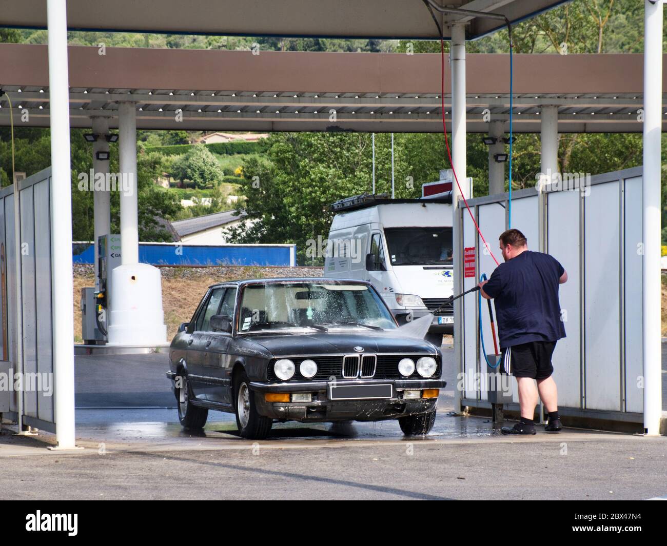 Mann, der die Lanze benutzt, um sein Auto bei einer Waschanlage mit Schaum zu sprühen. Stockfoto